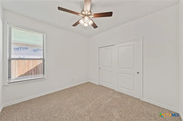 an empty room with a ceiling fan and a window