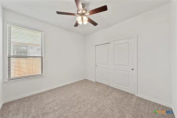 an empty room with a fan & a ceiling fan
