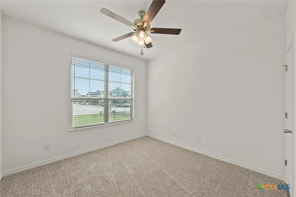 an empty room with a ceiling fan and a window
