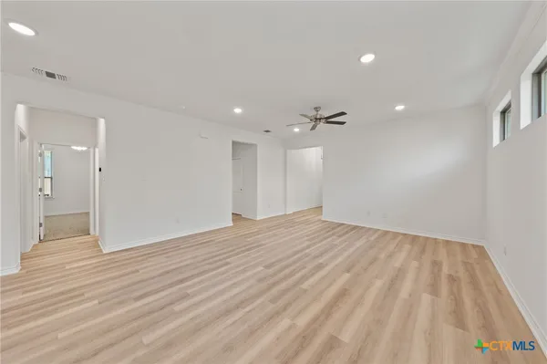 a large white kitchen with lots of counter top space a sink stainless steel appliances and cabinets