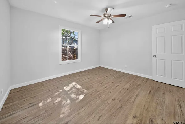 a view of a big room with wooden floor and a ceiling fan