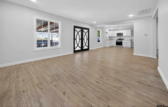 a view of an empty room with a window and wooden floor