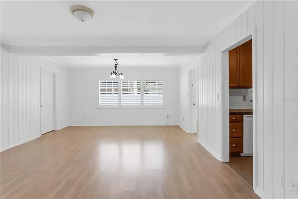 an empty room with wooden floor cabinet and windows
