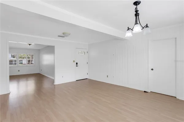 a view of an empty room with window and wooden floor