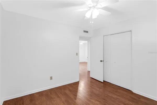 an empty room with wooden floor and fan