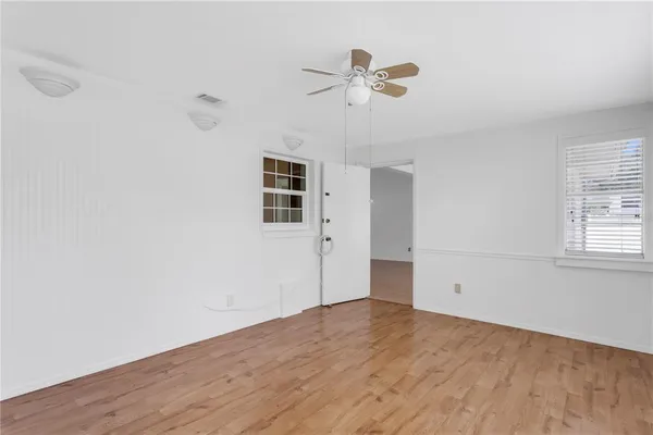 a view of empty room with wooden floor and fan