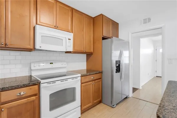 a kitchen with stainless steel appliances granite countertop a refrigerator and a stove top oven