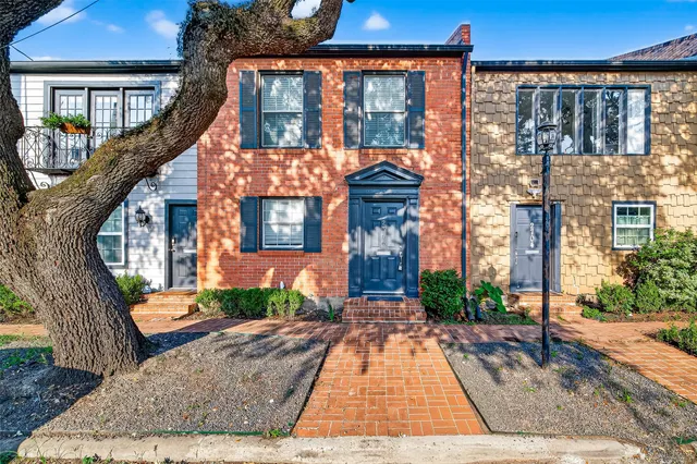 a view of a brick house with many windows next to a yard