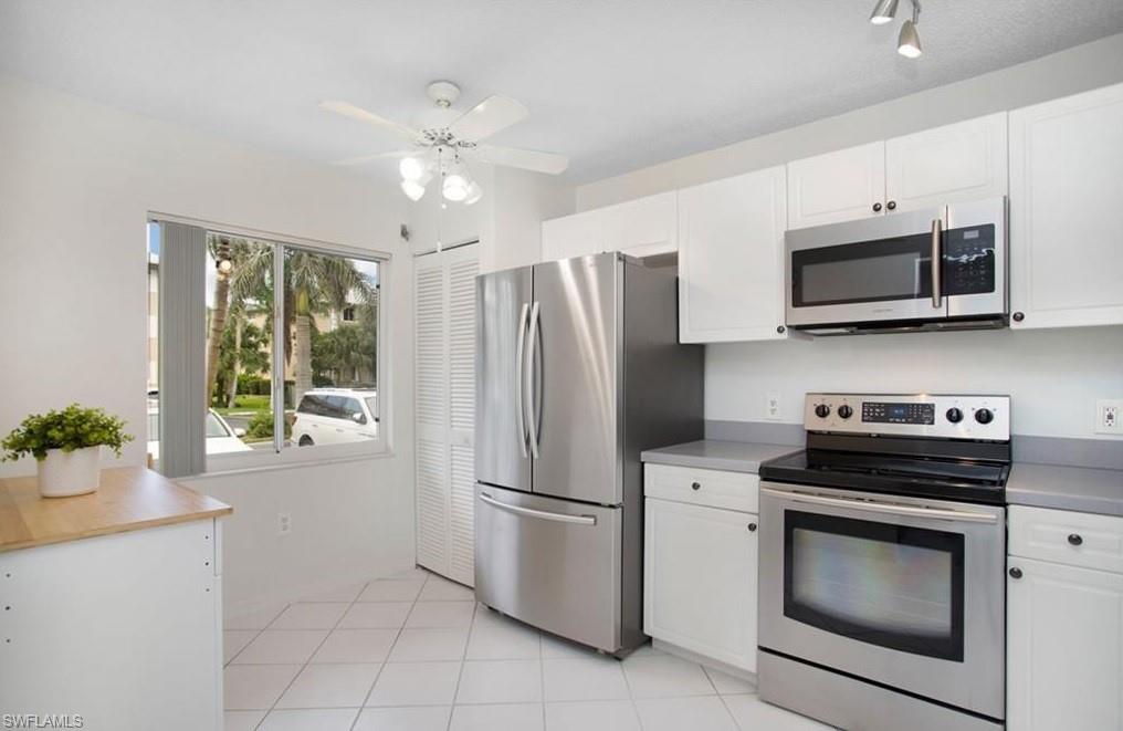 3012 Sandpiper Bay Circle, Unit D102 Naples, FL 34112 - Photo 3 of 13 a kitchen with stainless steel appliances white cabinets and a stove top oven
