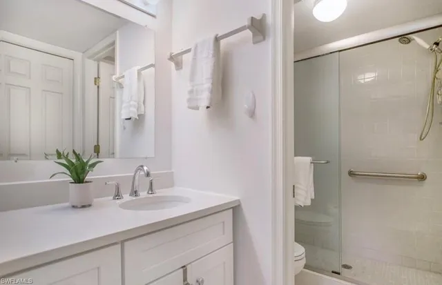 a bathroom with a granite countertop sink a toilet and shower