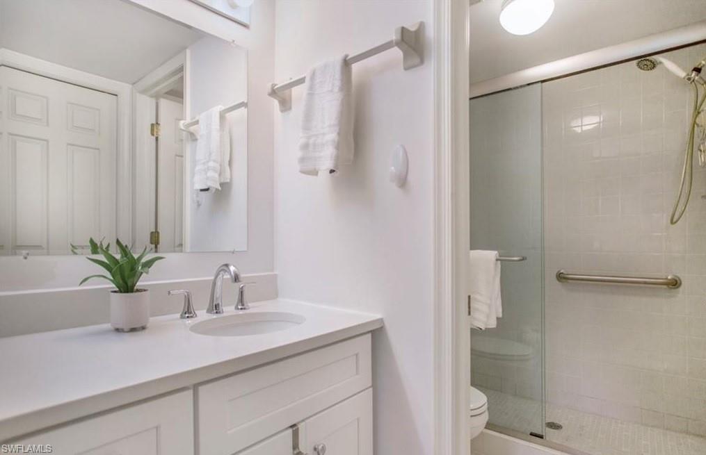 3012 Sandpiper Bay Circle, Unit D102 Naples, FL 34112 - Photo 8 of 13 a bathroom with a granite countertop sink a toilet and shower