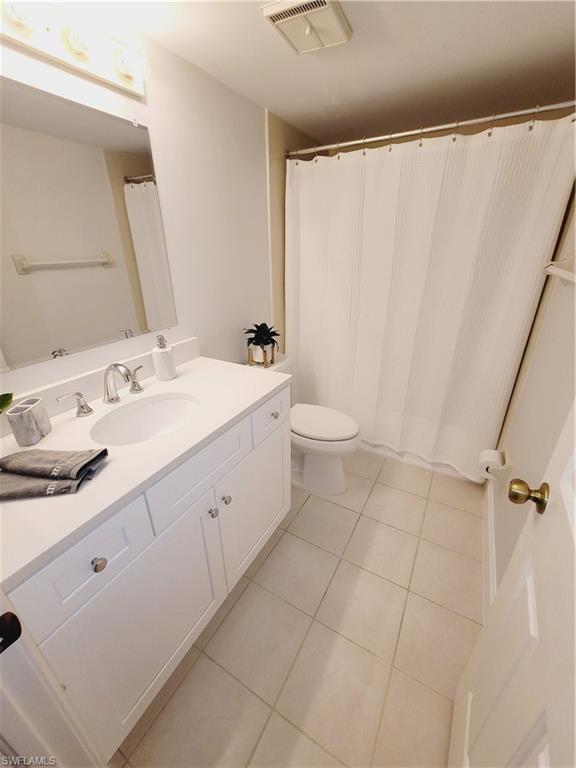 3012 Sandpiper Bay Circle, Unit D102 Naples, FL 34112 - Photo 10 of 13 a spacious bathroom with a double vanity sink toilet and a mirror