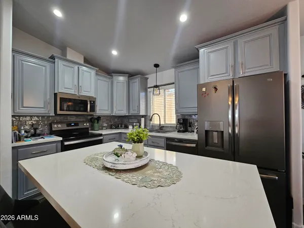 a kitchen with granite countertop a refrigerator and white cabinets
