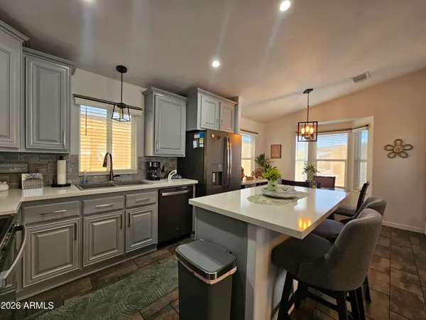 a kitchen with stainless steel appliances granite countertop a sink a stove a dining table and chairs
