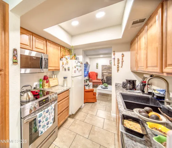a kitchen with granite countertop lots of clutter and stainless steel appliances