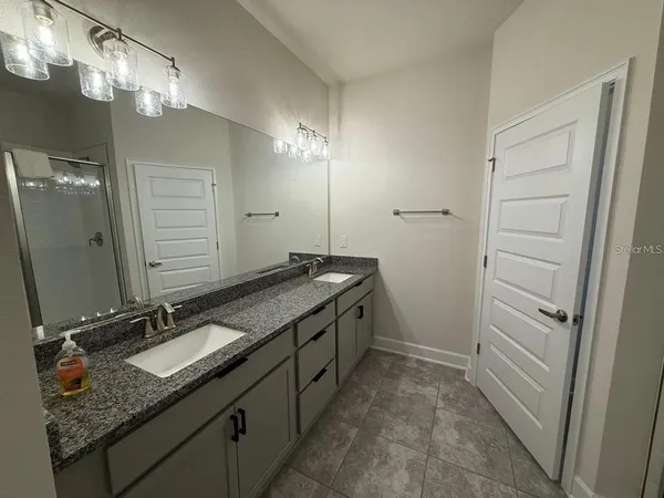 a bathroom with a granite countertop sink a mirror and shower