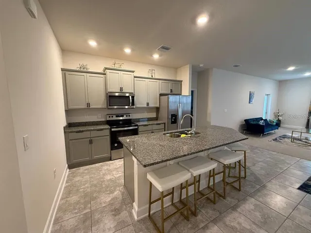 a kitchen with kitchen island a stove a table and chairs