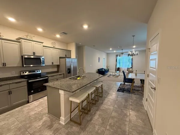 a kitchen with stainless steel appliances a stove a sink a refrigerator and white cabinets with wooden floor