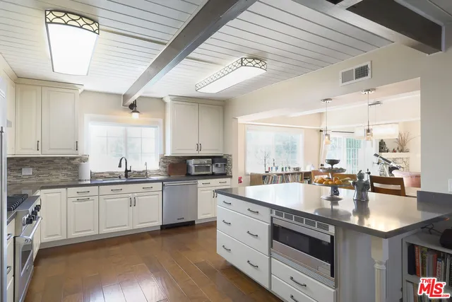 a large kitchen with stainless steel appliances granite countertop a lot of counter space and wooden floors