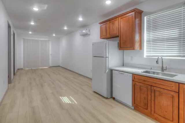 a view of a electric appliances in kitchen and empty room with wooden floor
