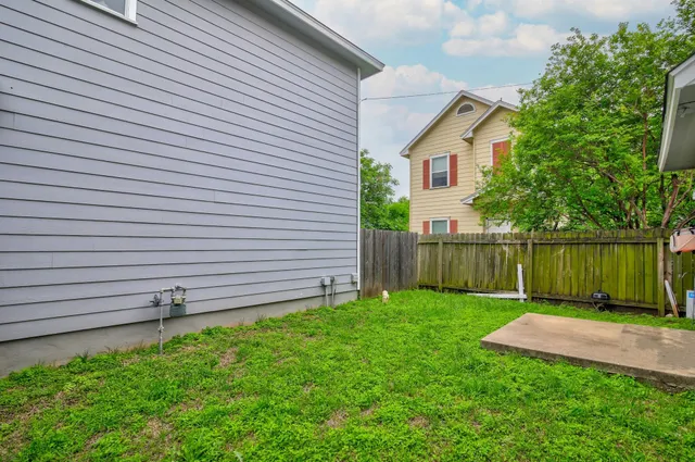 a view of a back yard of the house with a wooden fence