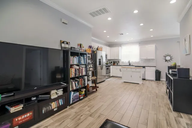 a living room with stainless steel appliances furniture and a flat screen tv