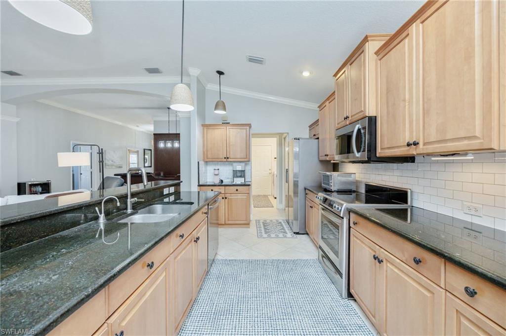 20350 Talon Trace Estero, FL 33928 - Photo 12 of 24 Kitchen featuring lofted ceiling, backsplash, light wood finish cabinetry, stainless steel appliances, and dark stone countertops