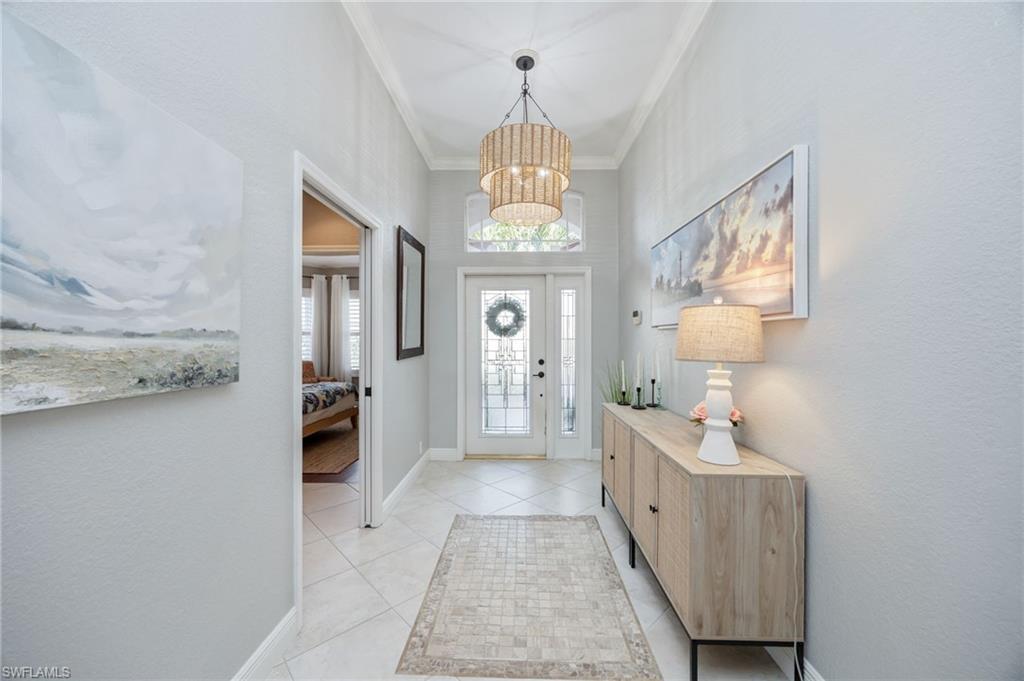 20350 Talon Trace Estero, FL 33928 - Photo 5 of 24 Entryway featuring a chandelier, ornamental molding, a textured wall, and light tile patterned flooring
