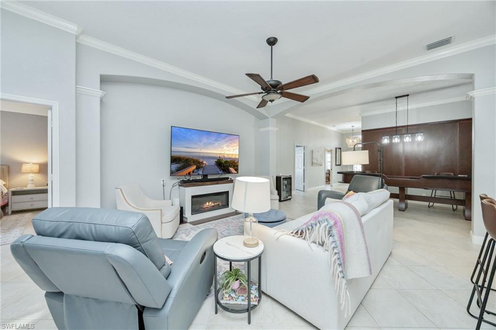 20350 Talon Trace Estero, FL 33928 - Photo 6 of 24 Living area with ornamental molding, ceiling fan, a glass covered fireplace, light tile patterned floors, and arched walkways