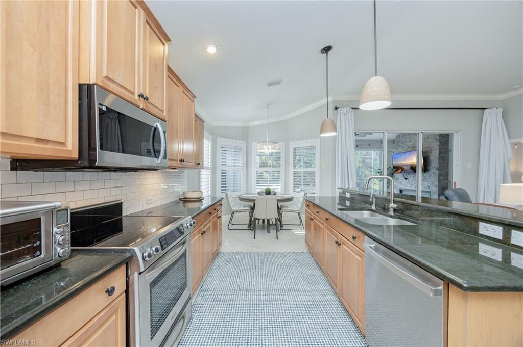 20350 Talon Trace Estero, FL 33928 - Photo 10 of 24 Kitchen with stainless steel appliances, crown molding, dark stone counters, pendant lighting, and tasteful backsplash
