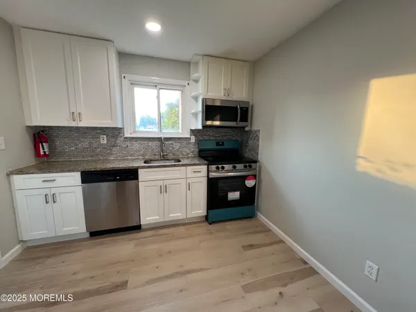 a kitchen with granite countertop a stove a sink and a microwave