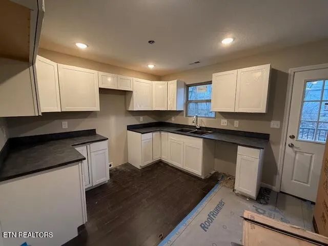 a kitchen with granite countertop white cabinets and black appliances