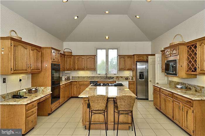11505 Big Piney Way Potomac, MD 20854 - Photo 8 of 29 a kitchen with stainless steel appliances granite countertop a stove top oven a sink dishwasher a dining table and chairs with wooden cabinets