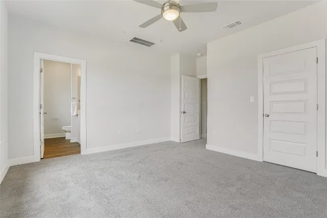 an empty room with closet and a ceiling fan