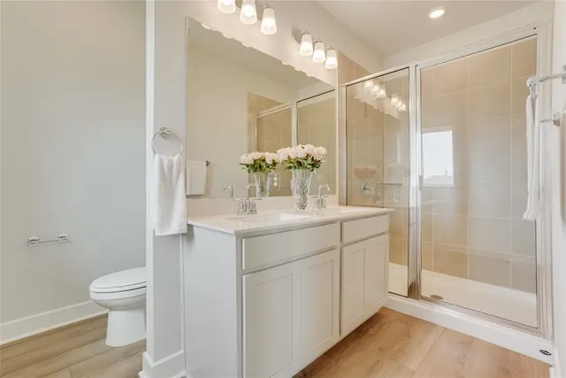 a bathroom with a shower sink vanity mirror and toilet