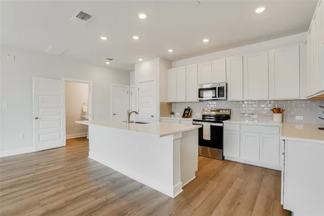 a large kitchen with cabinets wooden floor and stainless steel appliances