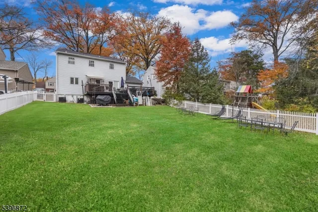 a view of a white house in front of a big yard with large trees