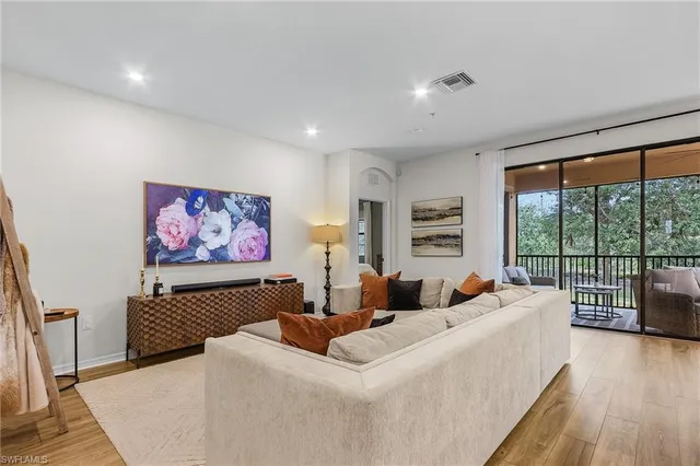 a living room with furniture large window and wooden floor