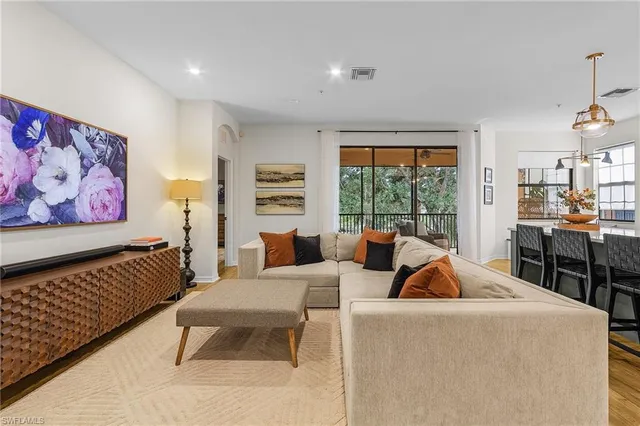 a living room with furniture a rug and a floor to ceiling window