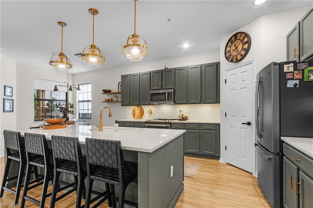 3793 Costa Maya Way, Unit 202 Estero, FL 33928 - Photo 2 of 28 a kitchen with a dining table a sink and a clock on the wall