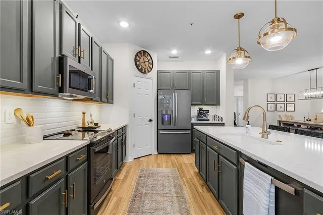 a kitchen with stainless steel appliances granite countertop a sink a stove top oven a refrigerator with wooden cabinets and floor