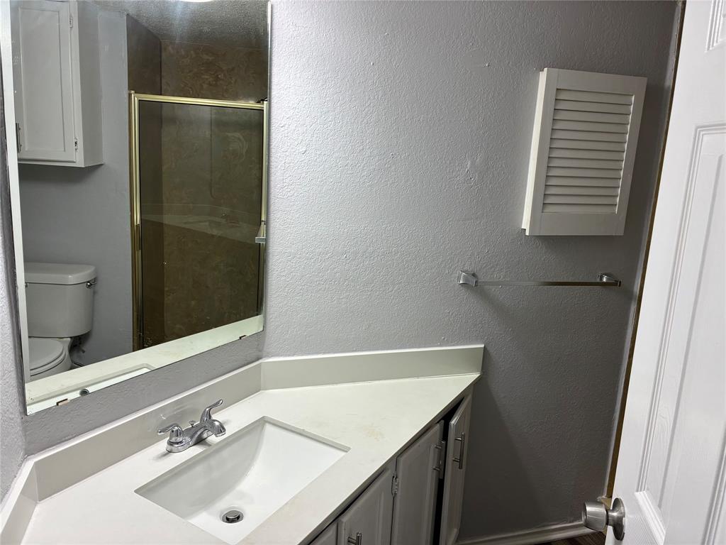 6108 Abrams Road, Unit 306 Dallas, TX 75231 - Photo 11 of 17 Bathroom featuring a textured wall, vanity, and a shower stall