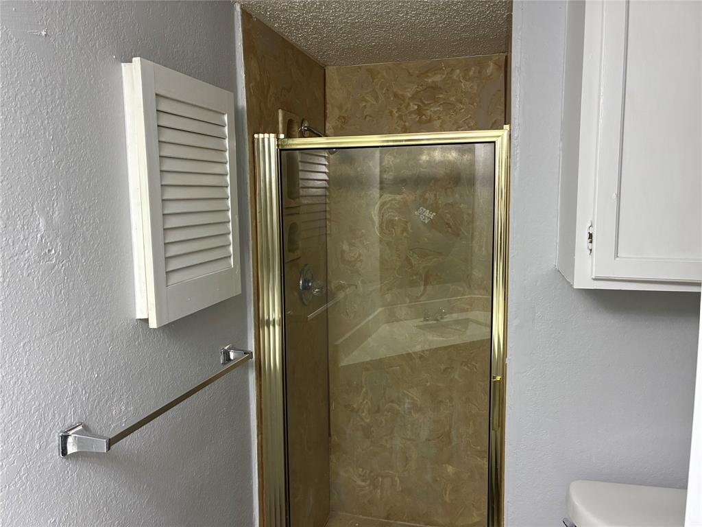 6108 Abrams Road, Unit 306 Dallas, TX 75231 - Photo 12 of 17 Full bathroom featuring a textured wall, a textured ceiling, and a stall shower