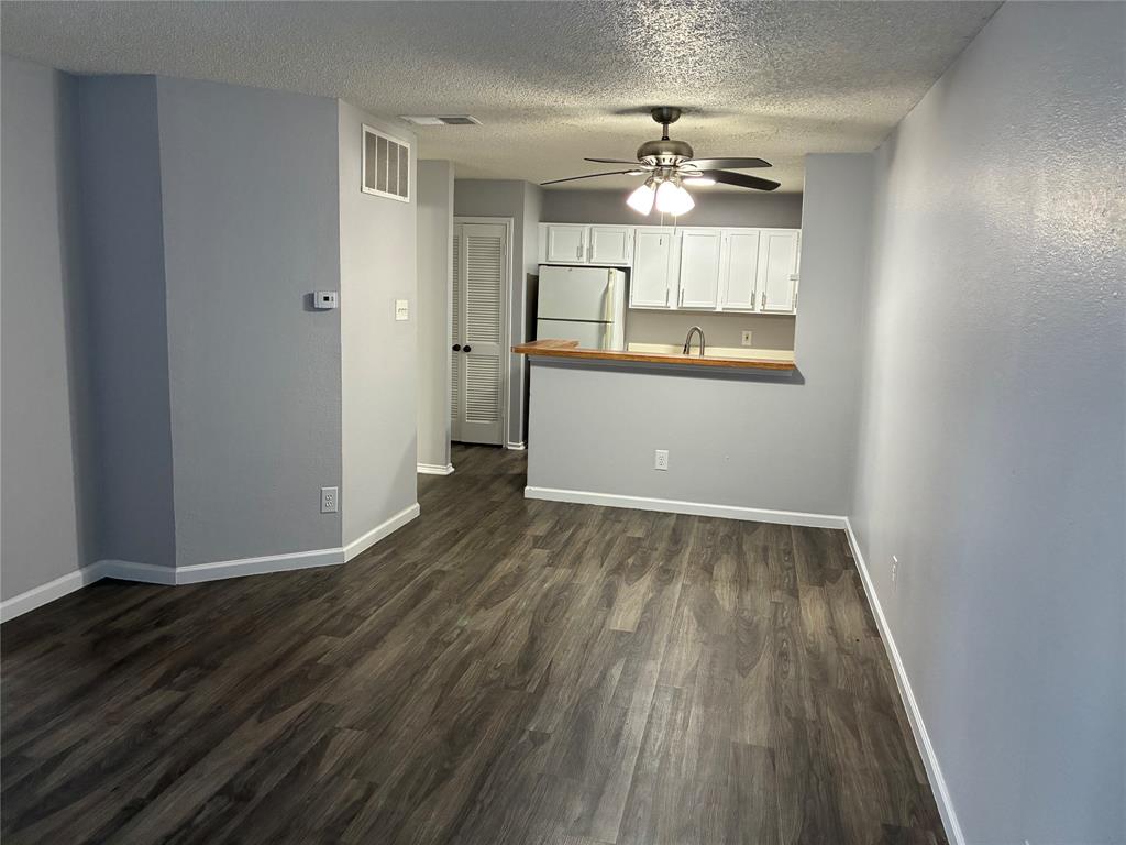 6108 Abrams Road, Unit 306 Dallas, TX 75231 - Photo 2 of 17 Unfurnished living room featuring a textured ceiling, dark wood-type flooring, and a ceiling fan