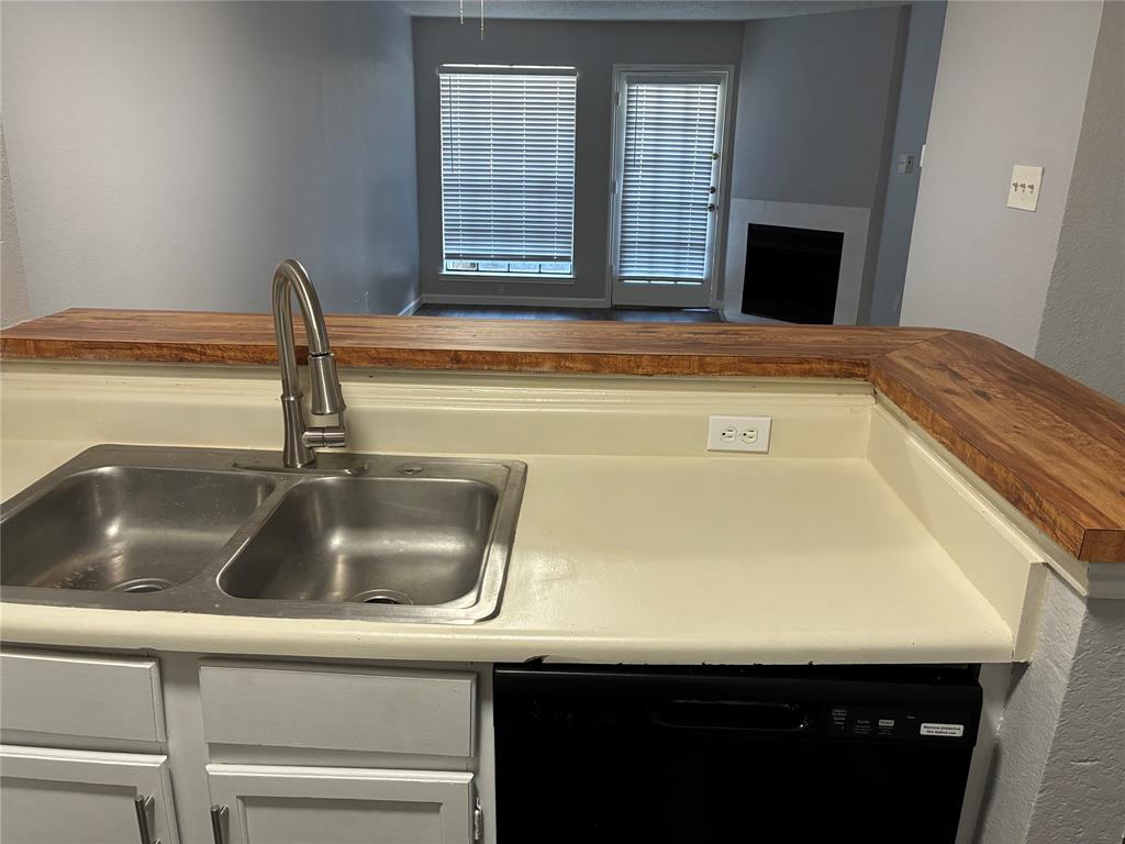 6108 Abrams Road, Unit 306 Dallas, TX 75231 - Photo 6 of 17 Kitchen with dishwasher, wood counters, a textured wall, and white cabinets