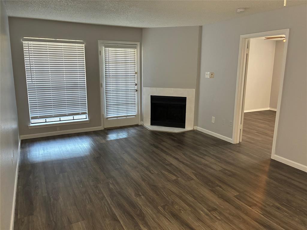 6108 Abrams Road, Unit 306 Dallas, TX 75231 - Photo 9 of 17 Unfurnished living room with a fireplace, a textured ceiling, and dark wood-type flooring