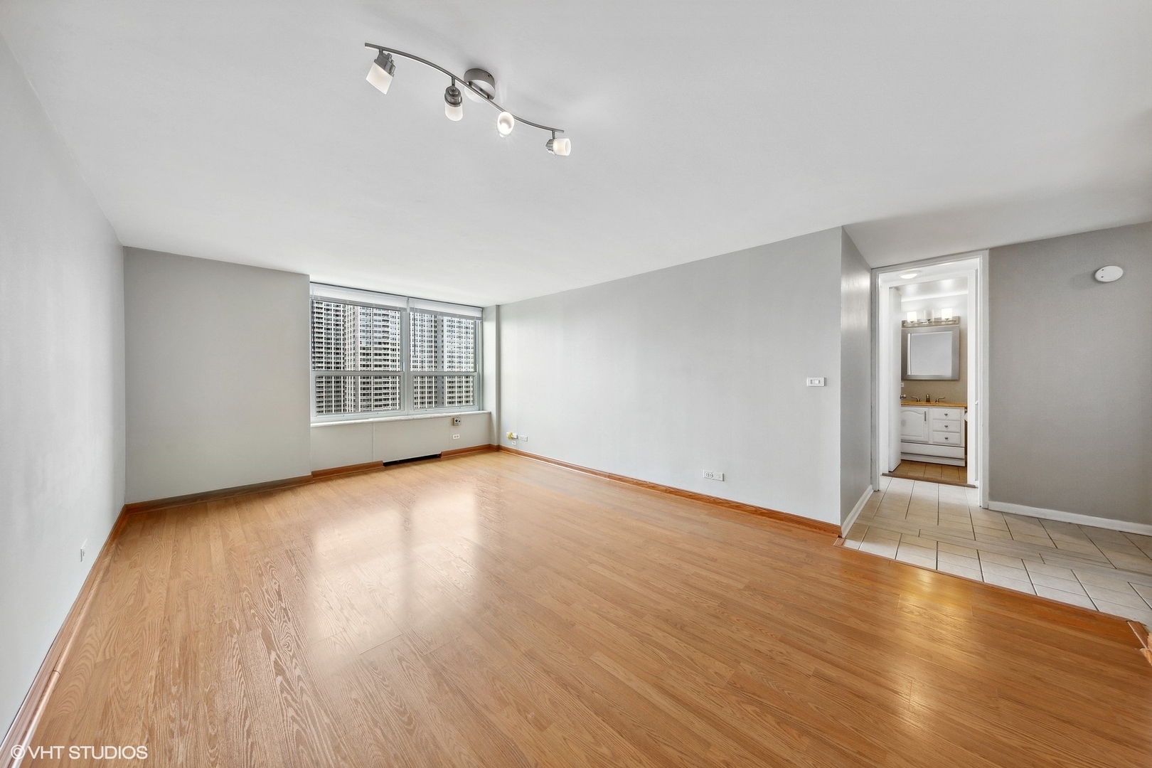 720 West Gordon Terrace, Unit 14F Chicago, IL 60613 - Photo 14 of 17 a view of an empty room with wooden floor and a window