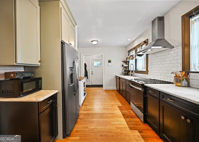 a large kitchen with stainless steel appliances a sink and cabinets