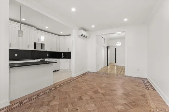 a large white kitchen with a sink and dishwasher a stove top oven with wooden floor
