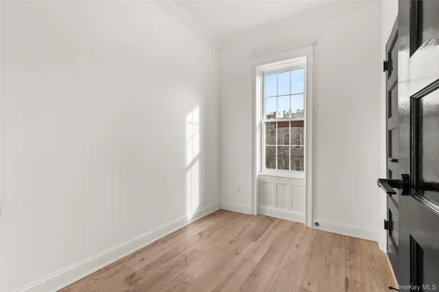 a view of an empty room with a window and wooden floor